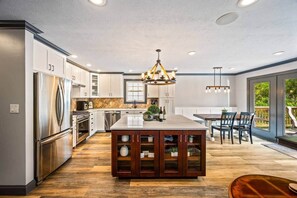 A modern kitchen with a central island, stainless steel appliances, and a dining area with a view.