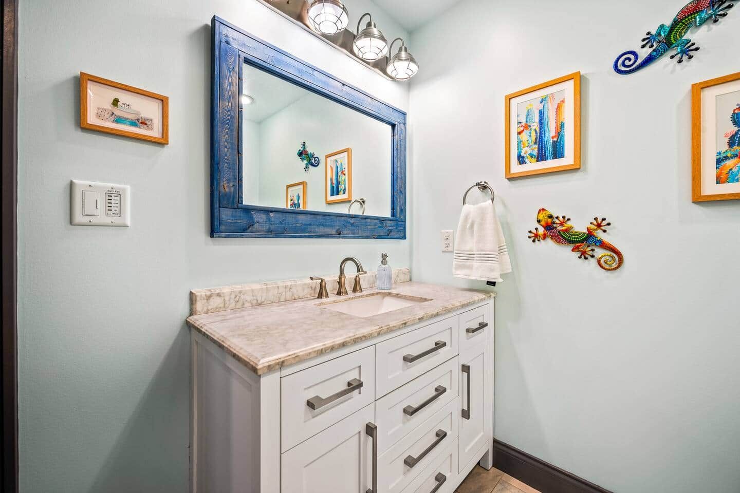 Un baño con un espejo grande, un lavabo y un perchero para toallas.