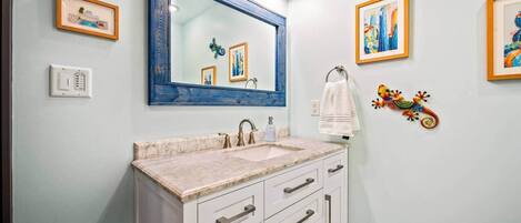 Un baño con un espejo grande, un lavabo y un perchero para toallas.