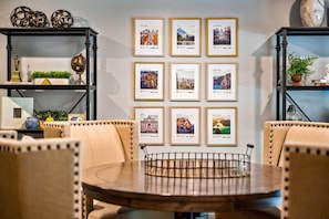 A dining area with a round table, chairs, and framed cityscape photographs on the wall.