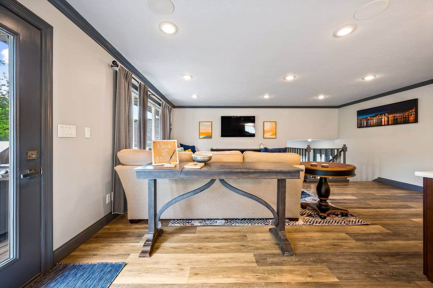 A modern living room with a sofa, a dining table, and a kitchen area in the background.