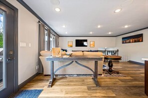 A modern living room with a sofa, a dining table, and a kitchen area in the background.