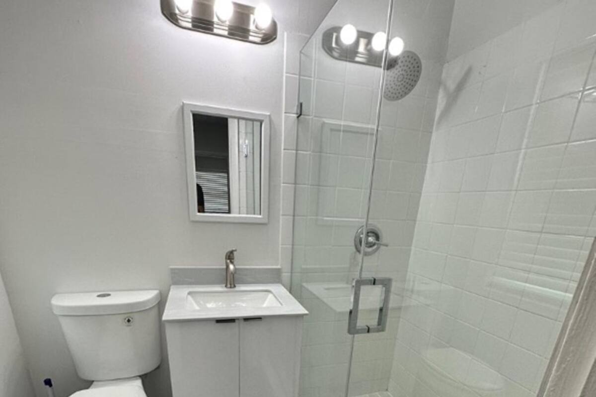 A modern bathroom with a toilet, sink, and glass-enclosed shower.
