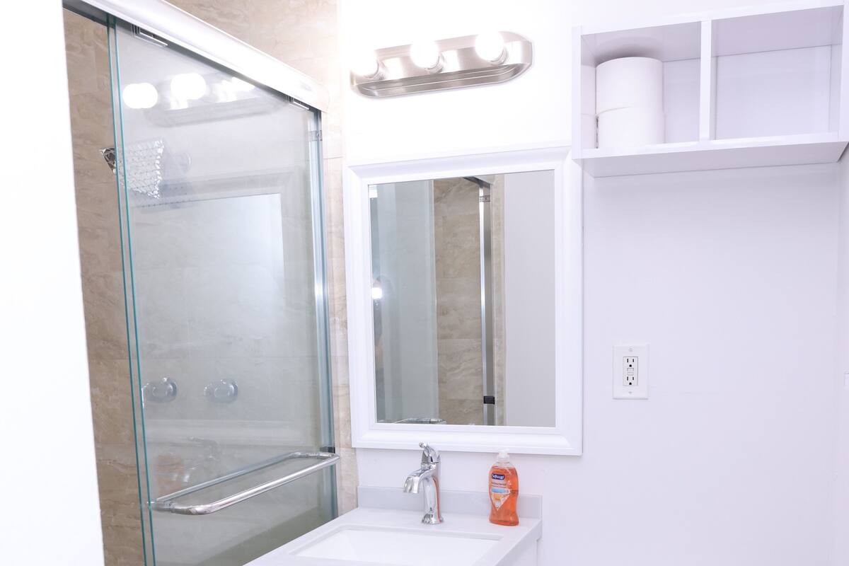 A modern bathroom with a glass shower enclosure, a white sink, and a toilet.