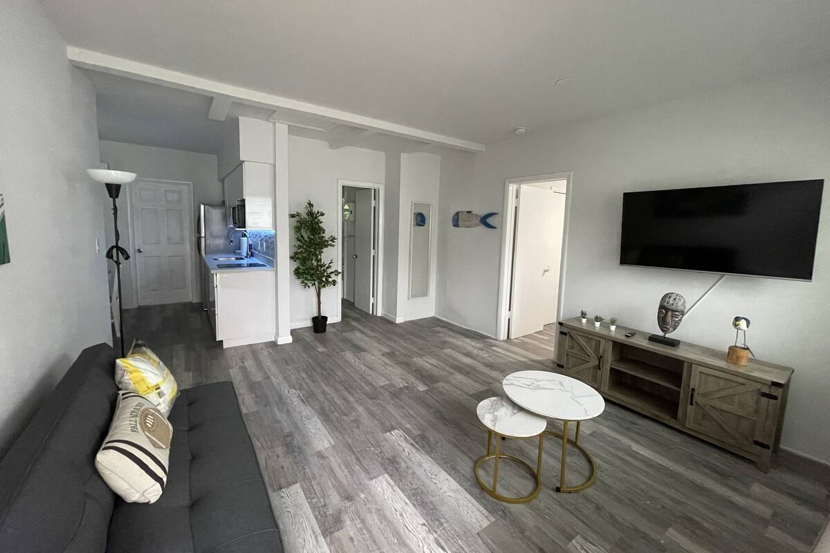 A modern living room with a grey sofa, a small coffee table, and a TV mounted on the wall.