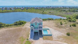 A large house with a swimming pool and a view of a lake. - Soundside Dog Friendly Home w/ Private Pool, Hot Tub, Elevator, and Game Room (Avon)