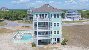 A multi-story building with a pool, surrounded by a beach and ocean views. - Soundside Dog Friendly Home w/ Private Pool, Hot Tub, Elevator, and Game Room (Avon)