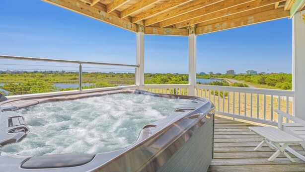 A hot tub on a wooden deck with a view of a water body and greenery. - Soundside Dog Friendly Home w/ Private Pool, Hot Tub, Elevator, and Game Room (Avon)