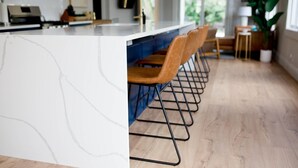 A modern kitchen with a white marble countertop, wooden chairs, and a wooden floor. - Fully renovated - 12ft island - 1.2G Wifi (Fort Lauderdale)