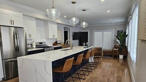 A modern kitchen with a central island, stainless steel appliances, and a bar area with stools. - Fully renovated - 12ft island - 1.2G Wifi (Fort Lauderdale)