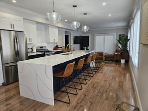 Een moderne keuken met een marmeren eiland, roestvrijstalen apparatuur en hanglampen.
