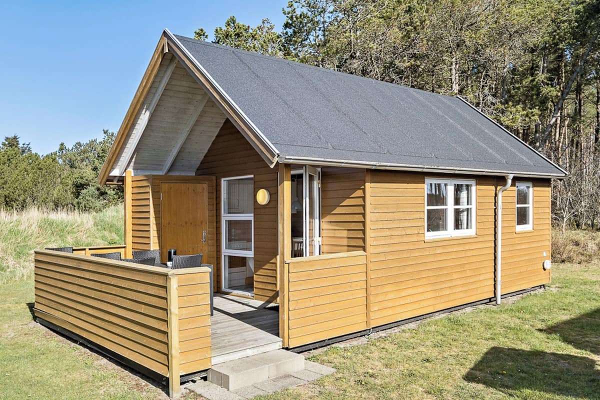 A small wooden cabin with a sloped roof, a front door, and a small porch area.