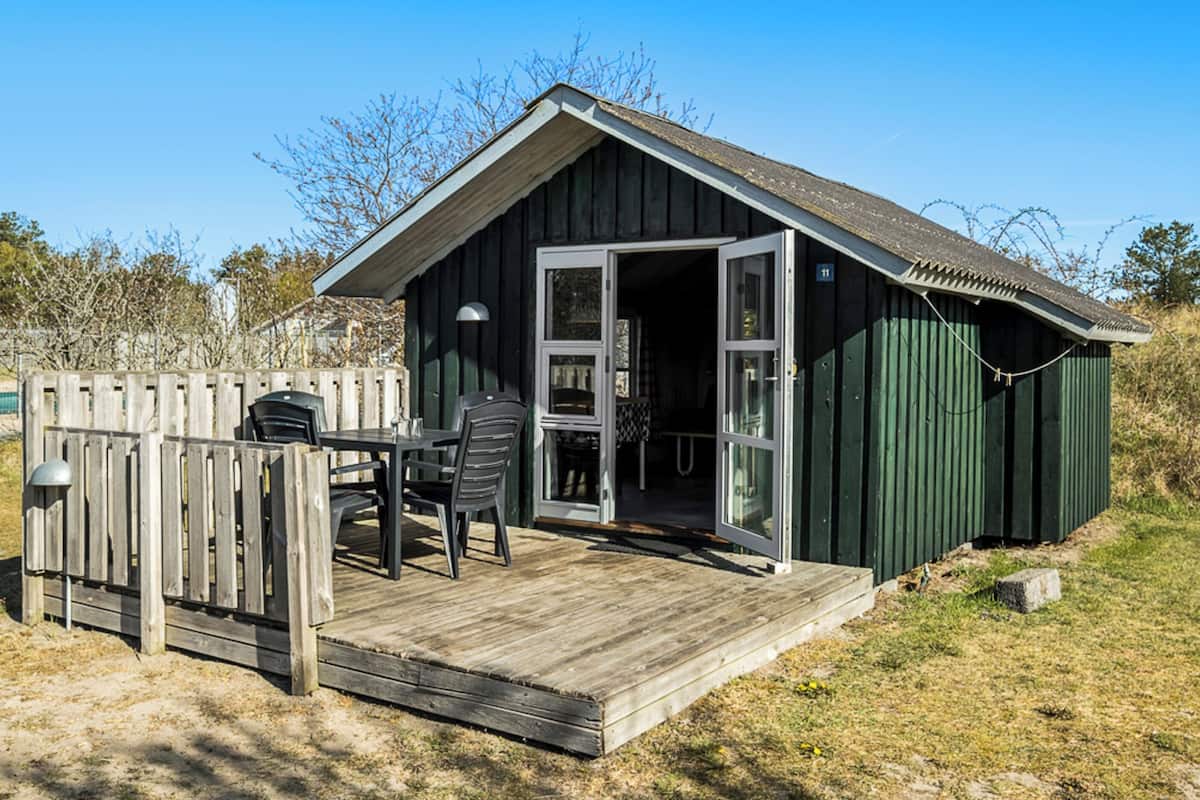 A small wooden cabin with a deck and a table with chairs.