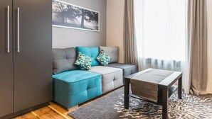 Un salon moderne avec un canapé gris, des coussins d’accent de couleur turquoise, une table basse en bois et un tapis à motifs.