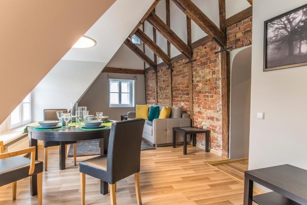 A dining area with a round table set for six, a sofa, and a brick wall.