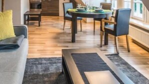 En åben stue i loftstil med spiseområde, køkken og trappe til en etage ovenover.