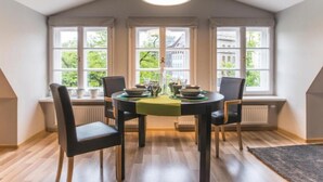 Spiseområde med et bord til fire, store vinduer og et skråt loft.