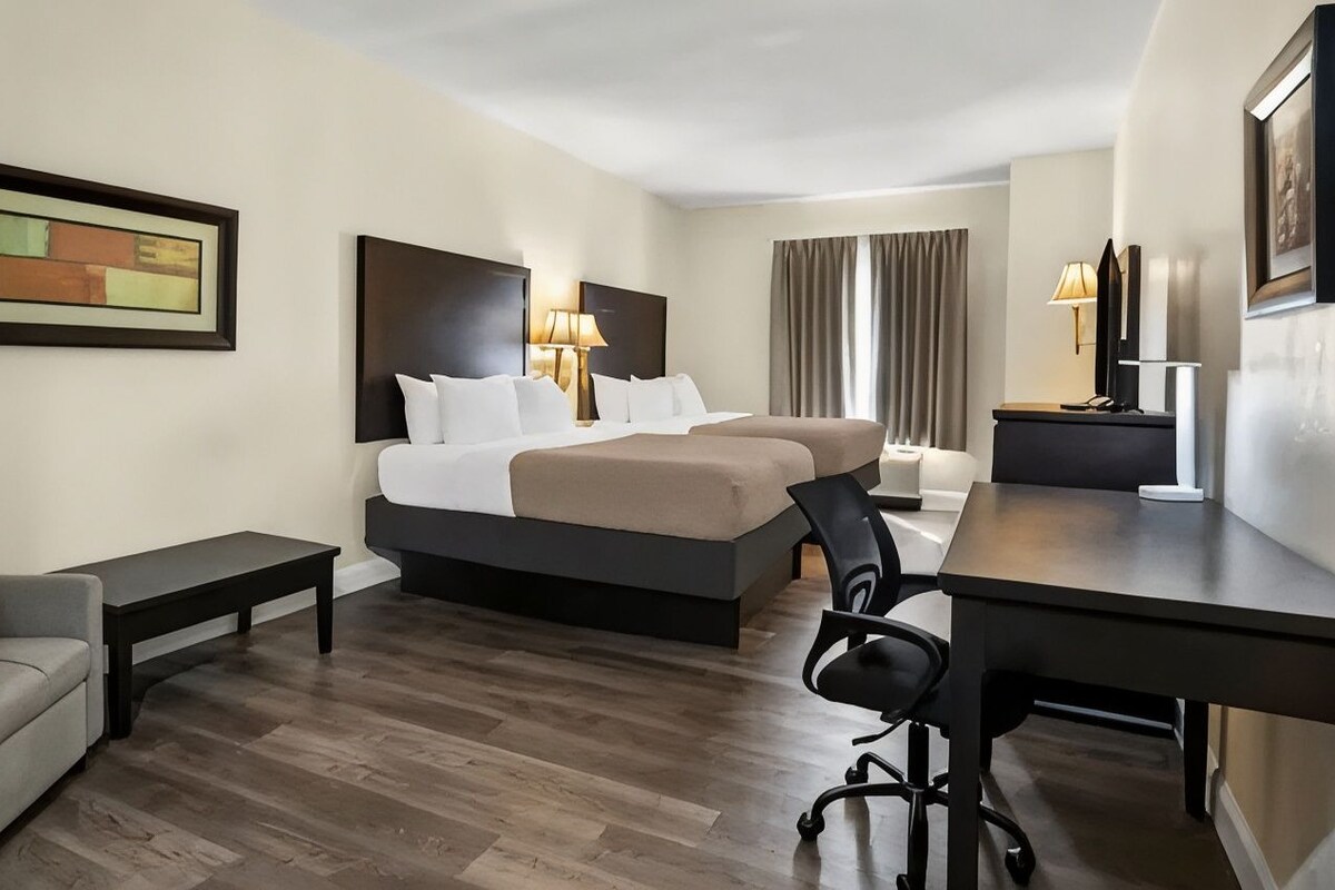 Ein Hotelzimmer mit einem Bett, einem Schreibtisch, einem Sessel, einem kleinen Tisch und einer Couch.
