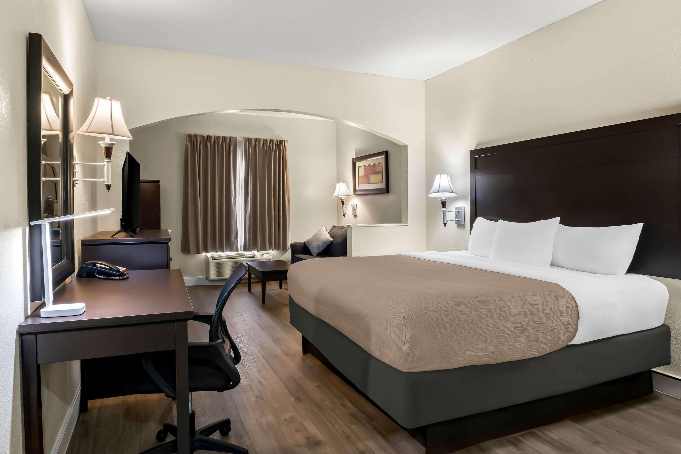Habitación de hotel con cama, escritorio, silla y televisión.