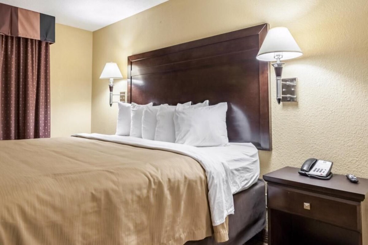 Ein Hotelzimmer mit einem großen Bett, einem Nachttisch mit Telefon und einer Wandlampe.