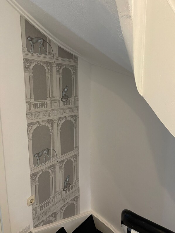 Un couloir orné d’un mur décoratif présentant un motif répétitif représentant un singe et des éléments d’architecture classique.