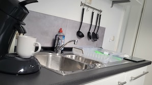 Una cucina con una macchina da caffè, una tazza, un lavandino e un espositore per piatti.
