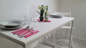 Un tavolo da pranzo con piatti, posate, bicchieri e una bottiglia, su un tavolo bianco con una sedia.