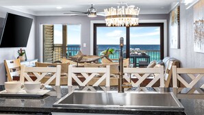 Une cuisine moderne dotée d’un grand îlot central, d’un lustre et offrant une vue sur l’océan.