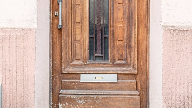 Una porta de fusta amb un pom de metall i una placa identificadora.