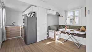 A compact kitchen with a built-in refrigerator, a sink, and a window overlooking a residential area. - First Camp Hasmark Strand Fyn (Otterup)