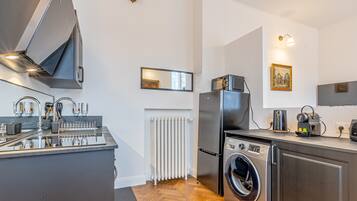 Eine moderne Küche mit Einbauherd, Mikrowelle, Kühlschrank und Waschmaschine.