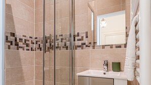A modern bathroom with a glass shower enclosure, a white sink, and a mirror above it. - Rock in Share - Le Grain de Sable (Thionville)