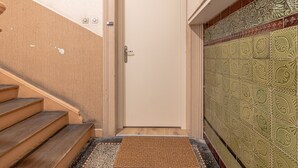 A door with a doorknob, a wooden staircase, and a patterned tiled wall. - Rock in Share - Le Grain de Sable (Thionville)