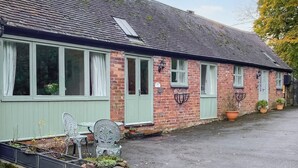 A brick house with green shutters, a tiled roof, and a paved driveway.
