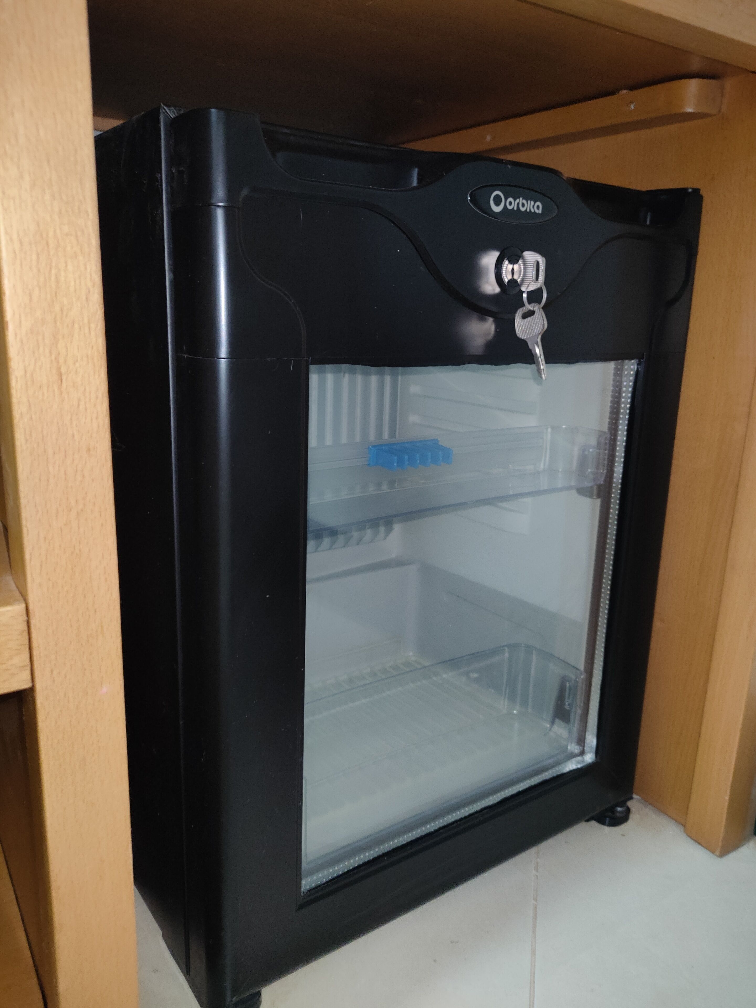 A black refrigerator with a glass door, a key slot, and a blue object inside.