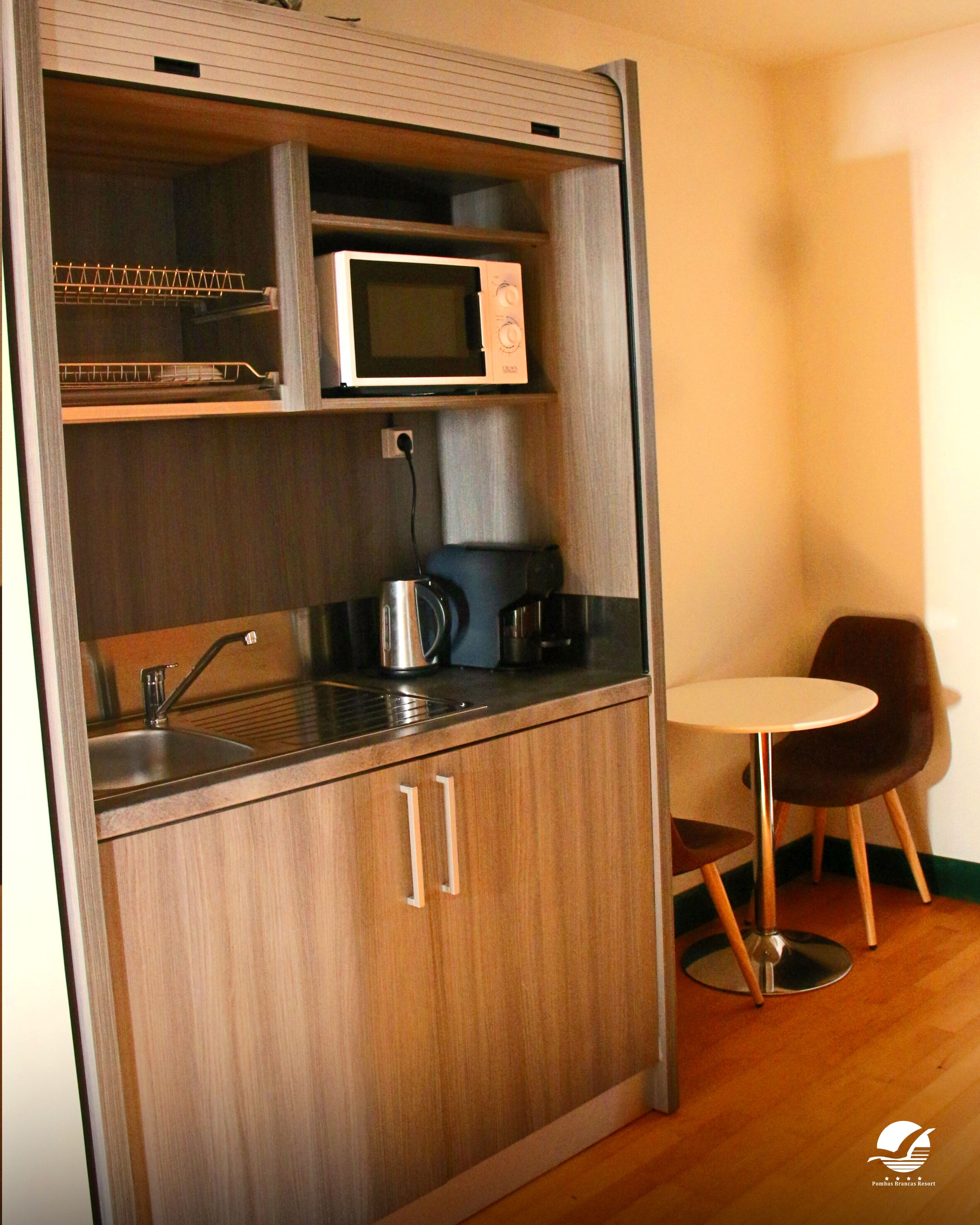 A compact kitchenette with a microwave, coffee maker, and a small sink.