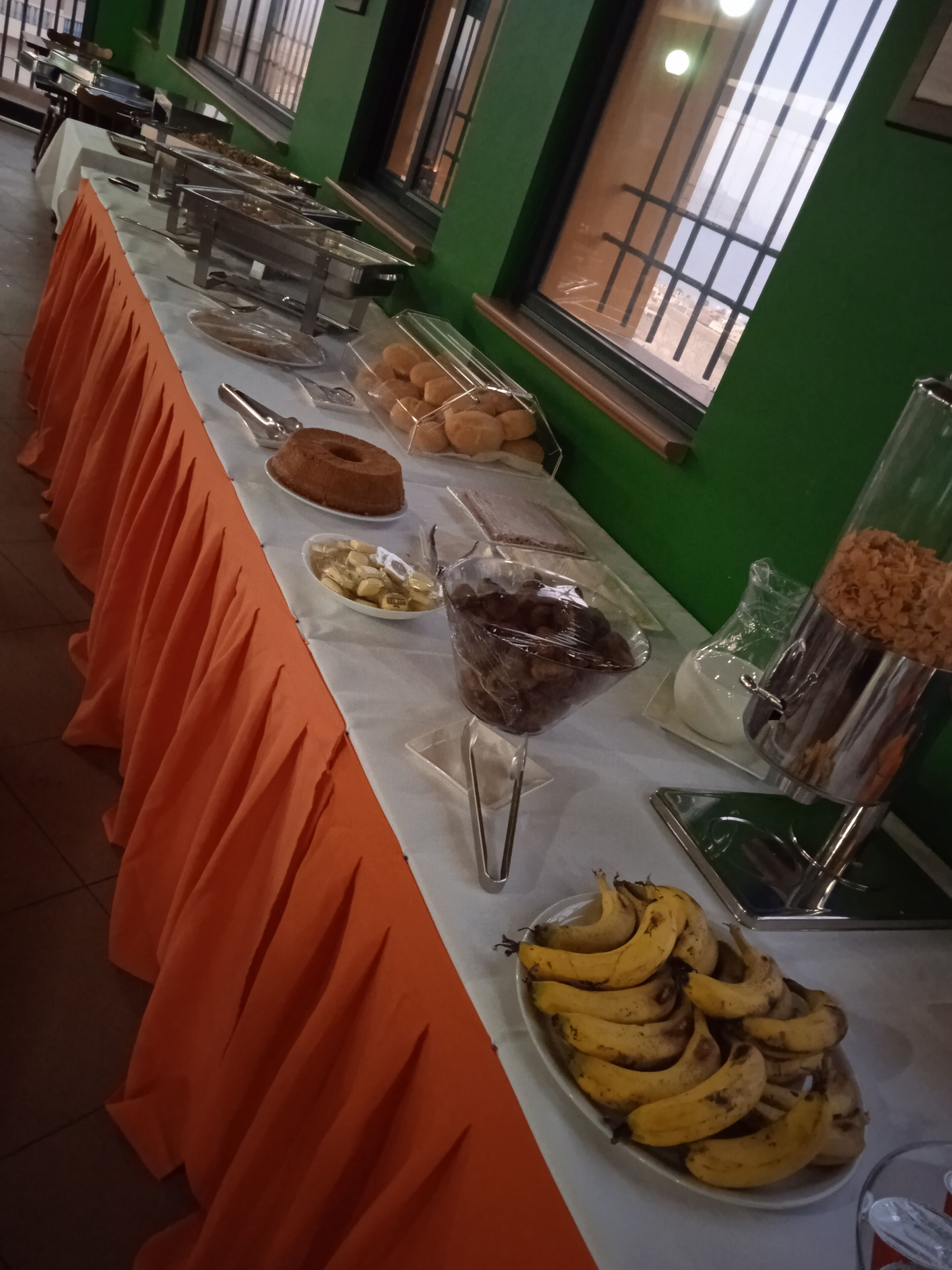 A buffet table with various food items and a fruit bowl.