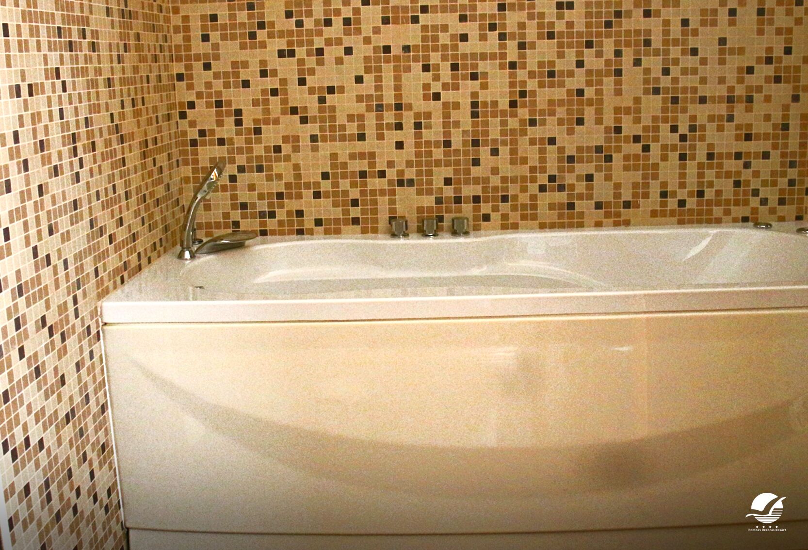 A bathroom with a large bathtub, tiled walls, and a faucet.