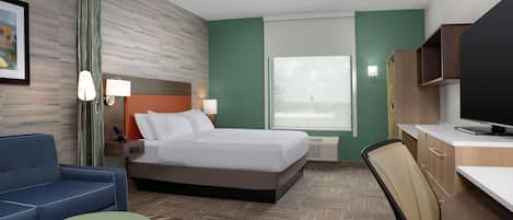A hotel room with a bed, a desk, a chair, a sofa, and a television.