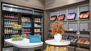 Un minibar de hotel con una variedad de bebidas, aperitivos y un cartel que indica Hilton Honors.