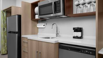 Una cocina moderna con un refrigerador de acero inoxidable, un microondas integrado, una cafetera y un lavavajillas.