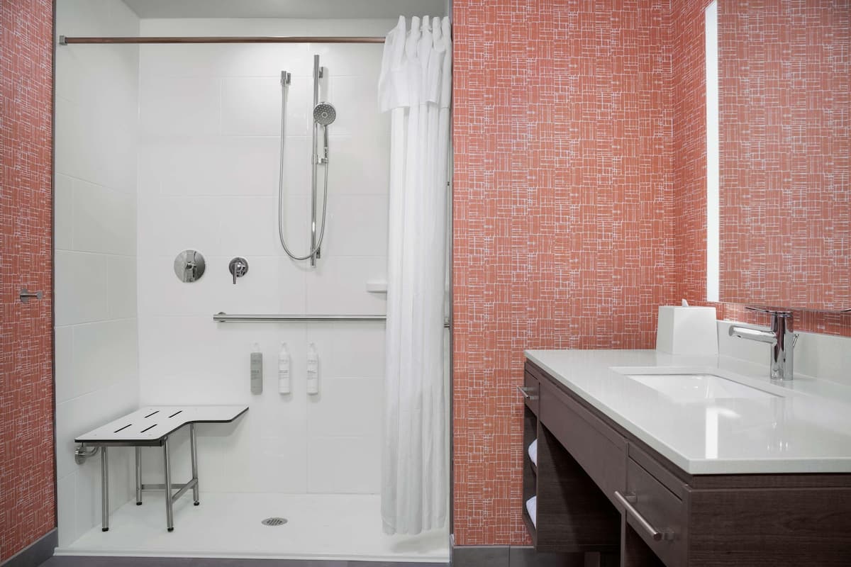 Un baño moderno con ducha, tocador con lavabo e inodoro.