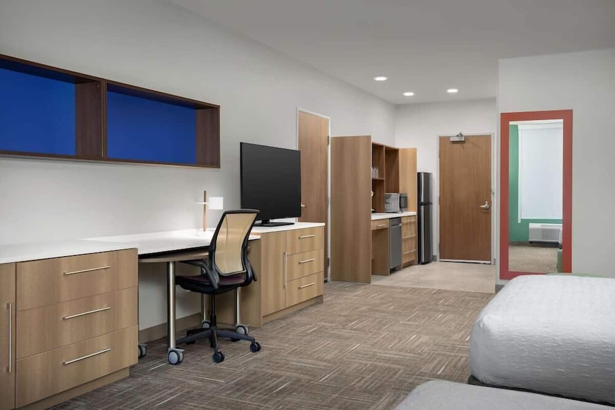 Una habitación de hotel con cama, escritorio, silla y televisor.