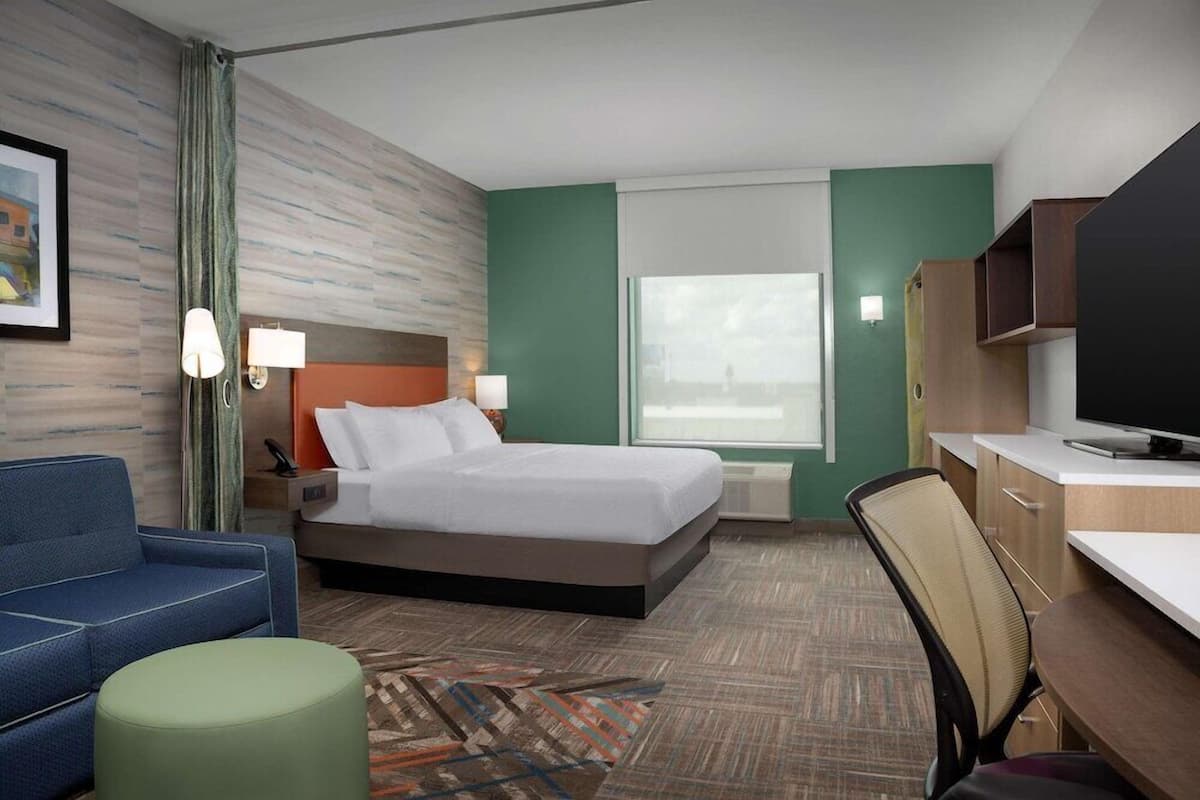Una habitación de hotel con cama, escritorio, sillón, sofá y televisión.