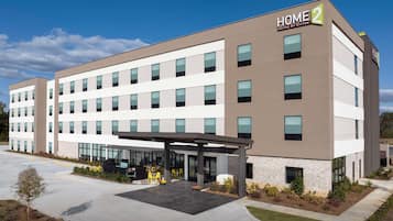 Un hotel moderno con un espacio exterior cubierto, varios pisos y cielo despejado.