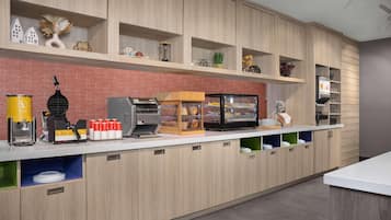 Cozinha moderna com armários de madeira, máquina de café, exposição de pão e diversos utensílios de cozinha.