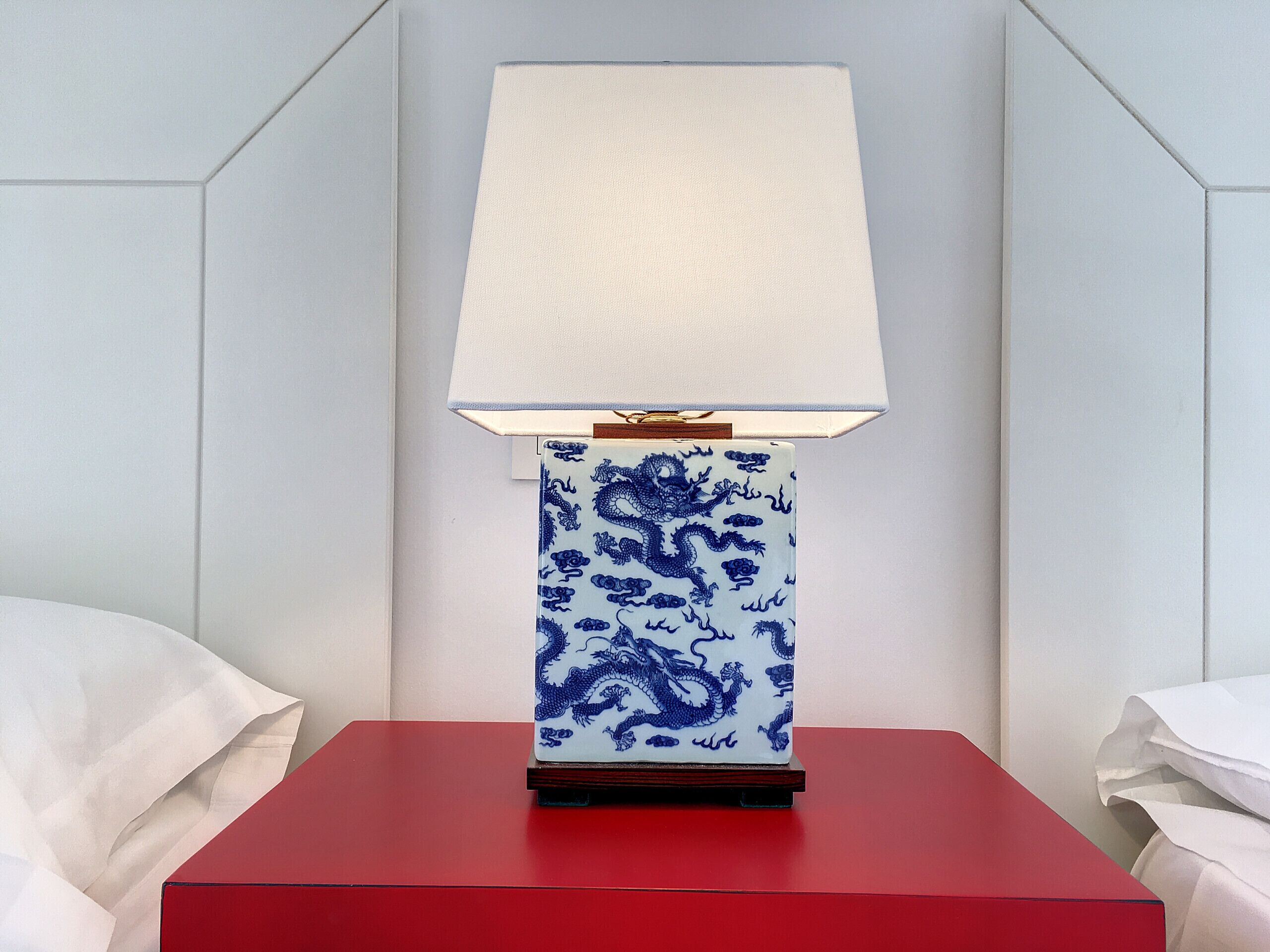 Een nachtkastje met een rode bovenkant en een lamp met een blauw-wit patroon.