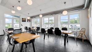 A modern classroom with large windows, black chairs, wooden tables, and hanging spherical lights. - First Camp Frigard   Flensborg Fjord (Krusaa)