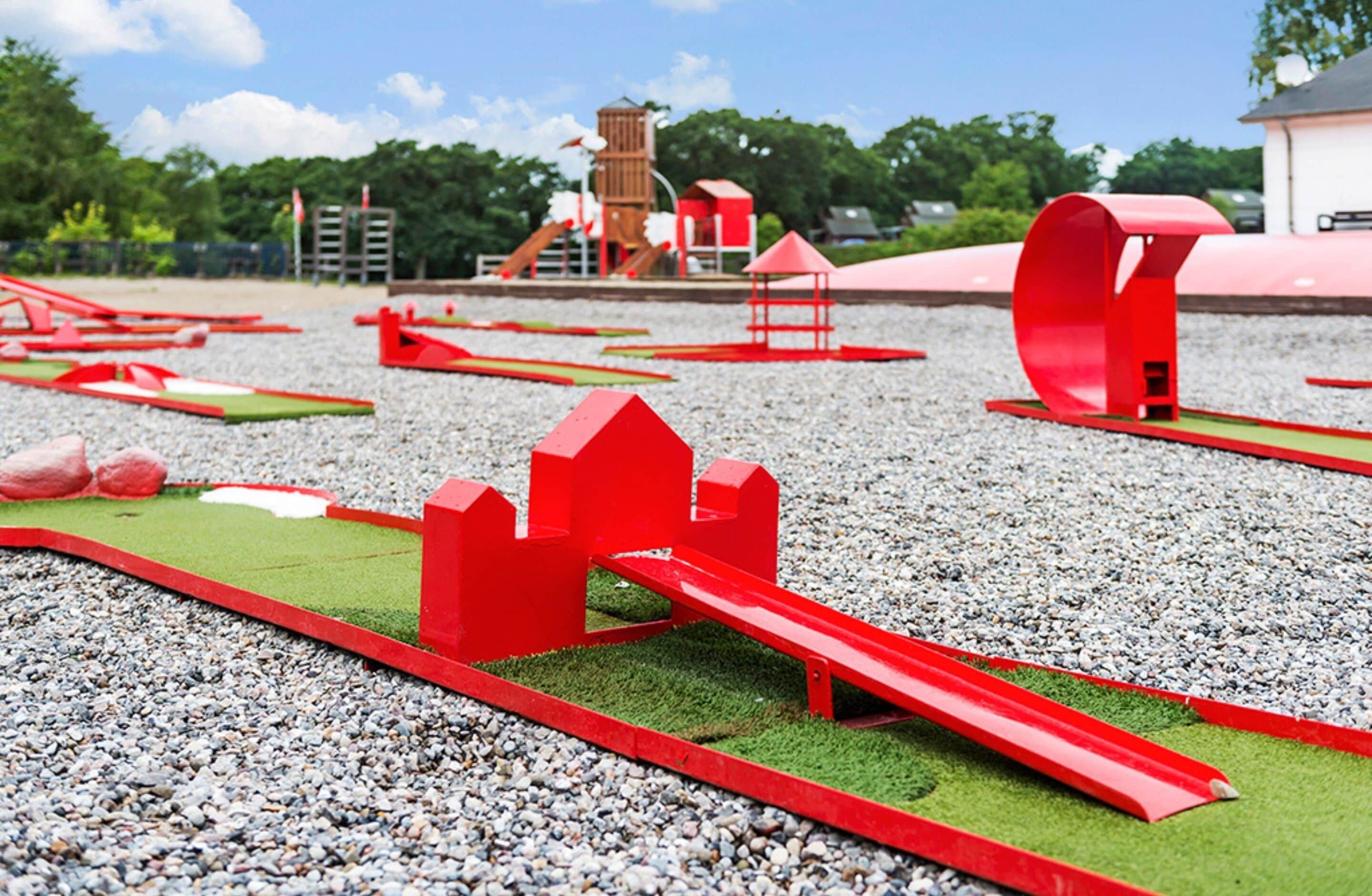 A playground with red structures and a wooden slide.