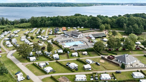 A campground with RVs, a swimming pool, and a large building with a roof. - First Camp Frigard   Flensborg Fjord (Krusaa)